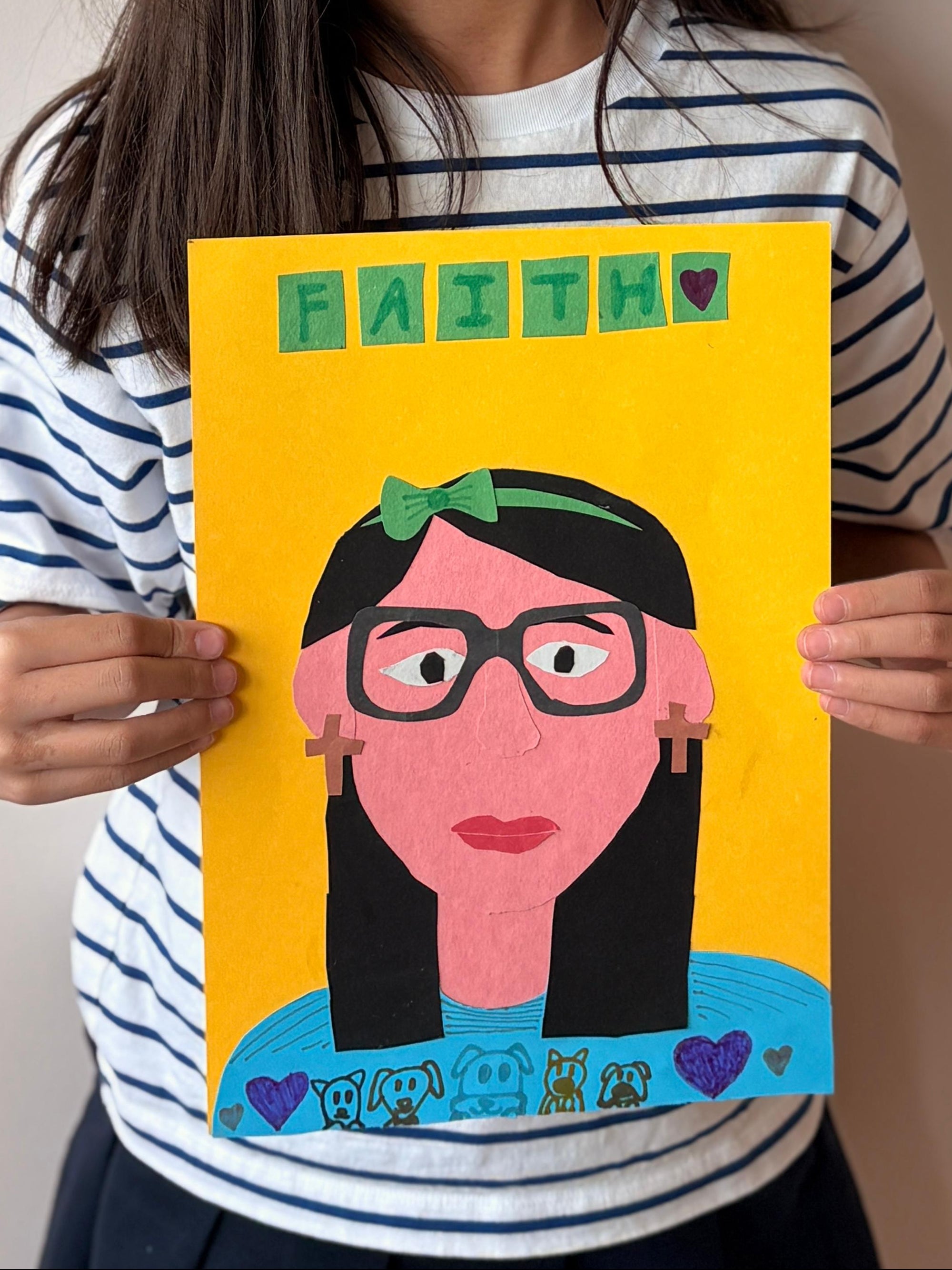 Young girl holding a drawing of herself with glasses against a plain background